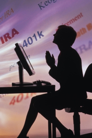 silhouetted woman sitting in front of her computer praying